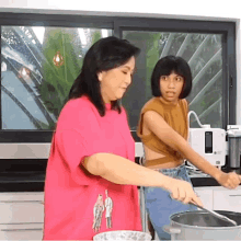 a woman in a pink shirt is stirring a pot with a spoon