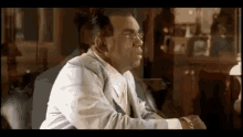 a man in a suit and tie is sitting at a table in front of a piano .