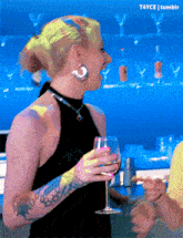 a woman with a tattoo on her arm is holding a glass of wine and laughing ..