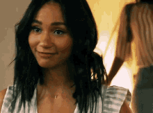 a woman is smiling and looking at the camera while wearing a striped shirt .
