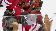 a hockey player with the number 8 on his jersey hugging another player