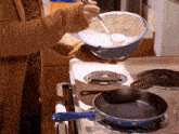 a person pouring something into a bowl on a stove top
