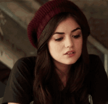 a woman wearing a burgundy knitted hat and a black t-shirt