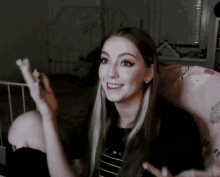 a woman in a black and white striped shirt is smiling and waving