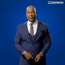a man in a suit and tie is standing in front of a blue background that says fox deportes on it