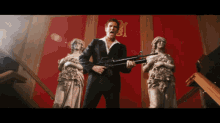 a man in a suit holds a gun in front of two statues with the letter m on the wall