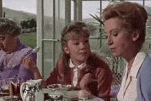 two women and a girl are sitting at a table eating