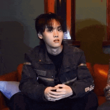 a young man is sitting on a couch with his hands outstretched and the word damn is above him