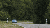 a blue porsche is driving down a road with motorweek.org written on the bottom