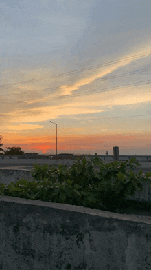 a sunset over a highway with a street light in the distance