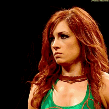 a woman with red hair is wearing a green and gold outfit .