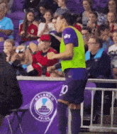 a soccer player with the number 10 on his shorts stands in front of a banner that says orlando pride