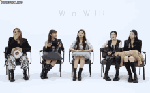 a group of girls are sitting in chairs with their legs crossed and a sign that says wow .