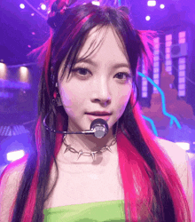a girl with red and black hair is wearing a green top and a microphone