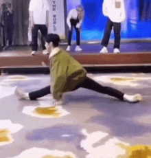 a person is doing a split on a stage with a sign that says the world behind them .