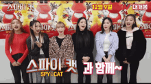 a group of girls are standing in front of a poster for spy cat