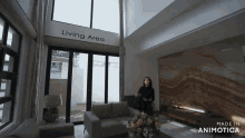 a woman is standing in a living room with a sign that says living area