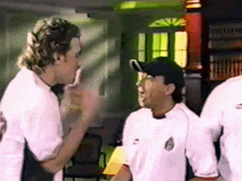 a group of men are standing in a room and one of them is wearing a white shirt with mexico on it