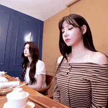 a woman in a striped off the shoulder shirt sits at a table