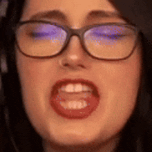 a close up of a woman wearing glasses and red lipstick making a face .