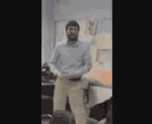 a man in a blue shirt and khaki pants is dancing in a room .