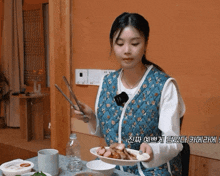 a woman in a blue vest holds a plate of food