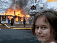 a young girl stands in front of a burning house with the number 38 on the back