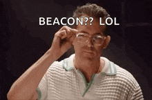 a man wearing glasses says beacon lol in a dark room .