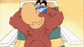 a cartoon character wearing sunglasses is sitting in a chair with his hands behind his head .