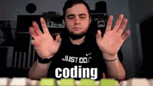 a man wearing a just do coding shirt is making a funny face .