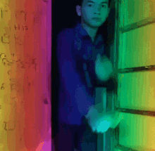 a man in a blue shirt stands in front of a wall with graffiti on it that says " i his on "