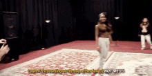 a woman is screaming at the top of her lungs while standing on a rug on a stage .