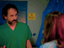 a woman in a blue gown stands in a hospital room