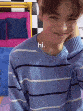a young man wearing a blue striped shirt says hi