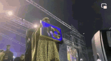 a man in a leopard print dress is holding a blue box with a picture of a woman on it