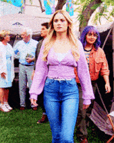 a woman in a purple top and blue jeans stands in front of a tent that says ' a ' on it