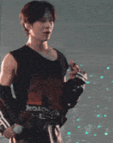 a man is holding a microphone while wearing a black tank top