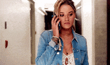 a woman in a denim jacket is talking on a cell phone .