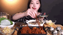 a woman is eating food with chopsticks and a spoon
