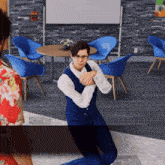 a man in a blue suit is kneeling in front of a fire extinguisher