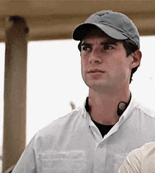 a man wearing a baseball cap and a white shirt is standing next to a woman .