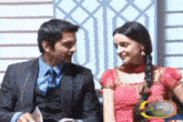 a man and a woman are sitting next to each other and the man is wearing a suit and tie