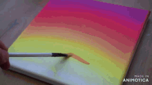 a person is painting a colorful rainbow on a canvas