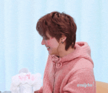 a person wearing a pink hoodie with korean writing on the bottom right