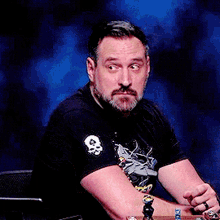 a man with a beard is wearing a black shirt with a skull and crossbones on it