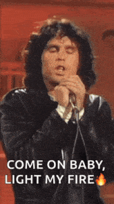 a man is singing into a microphone while wearing a leather jacket .