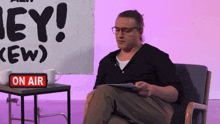 a man sits in a chair in front of a sign that says hey