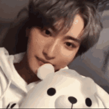 a young man is holding a teddy bear in his hand and eating it .