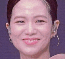 a close up of a woman 's face with a pink lip and earrings .