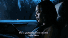 a woman is sitting in the back seat of a car looking at her phone